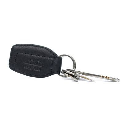 K10753AB | Key ring in genuine full grain leather, with light grain. Black colour. Polished nickel ring. Total dimensions: 3.5 x 9 x 0.5 cm. Packaging: Rigid bottom/lid gift box